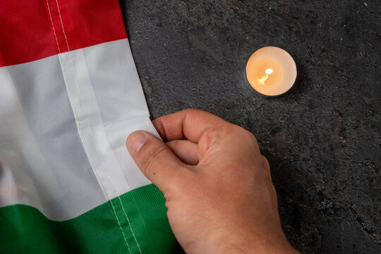 Hand Holding Hungarian Flag Next to Memorial Candle