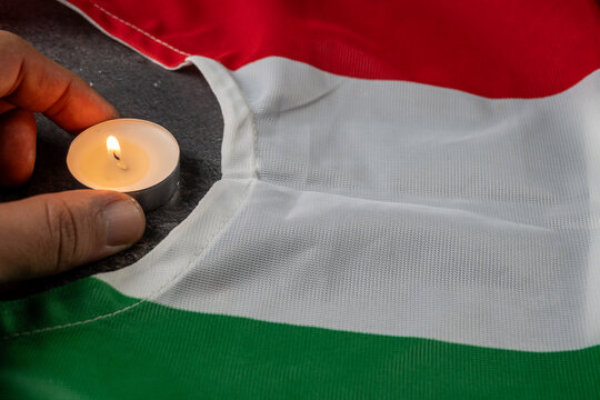 Memorial Candle Held Over Hungarian Flag