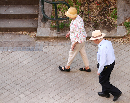 Se&ntilde;ores mayores de paseo con sombrero pareja de abuelos viejos andando elegantes y activos por acera calle