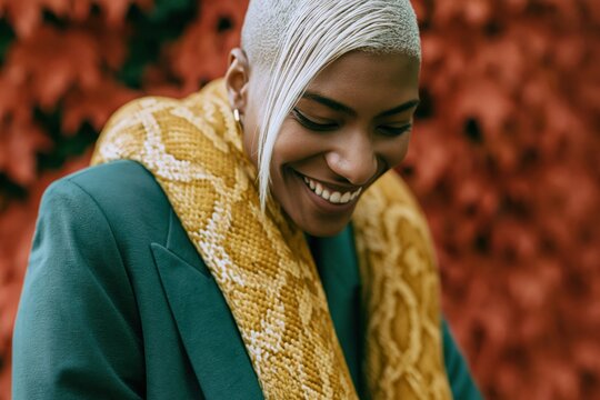 Smiling person with large yellow python scarf against red foliage for joyful portrait background and fashion banner design