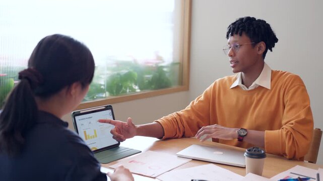 Diverse business colleagues discussing financial data and roadmap strategy on tablet computer in modern office