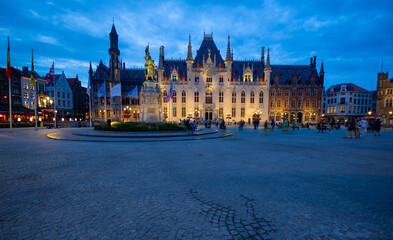 Fototapeta premium BRUGES, BELGIUM, JULY 14, 2025 - The Provinciaal Hof (Provincial Palace) by night located in the famous market square, the Markt, in the heart of Bruges, Belgium