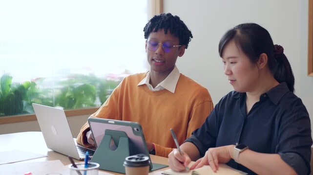 Diverse business colleagues discussing financial data and roadmap strategy on tablet computer in modern office
