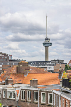 Rotterdam, Netherlands - 03 June 2026 - The iconic Euromast observation tower soaring into a cloudy sky above traditional orange tiled residential rooftops.