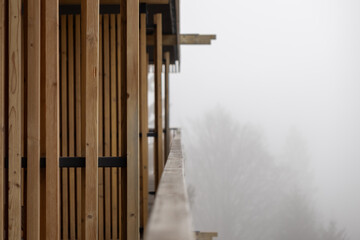 Fototapeta premium A vertical wooden slat facade on a balcony overlooking a dense fog, reflecting a minimalist architectural design that evokes tranquility and serene connection to the mountain nature