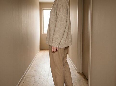 Professional woman walking in modern hallway. Stylish female model in beige business casual attire strolling indoors.