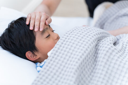 熱の子供を看病する母親