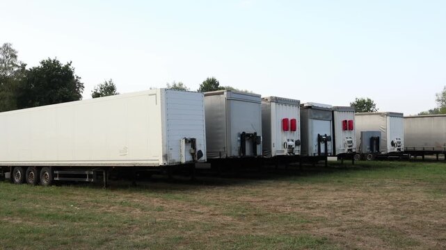 Row of parked semi trailers stands at logistics yard awaiting cargo transport representing freight distribution supply chain storage and commercial trucking
