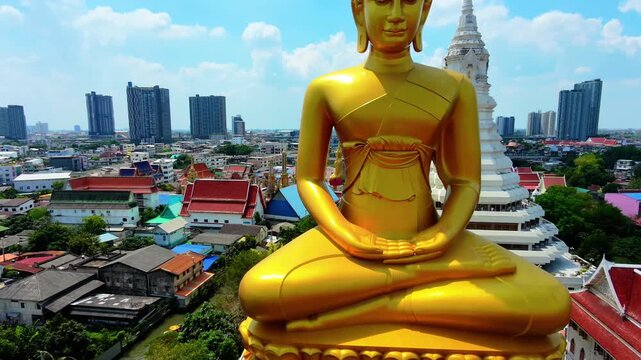 Aerial reveal shot rising and pulling back from Giant Golden Buddha statue at Wat Paknam Phasi Charoen, Bangkok, Thailand