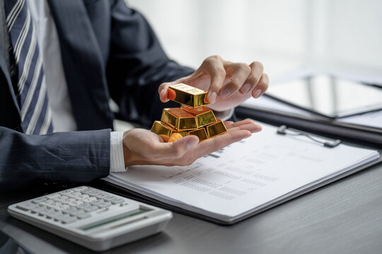A hand holds a gold bar for financial success and investment strategy