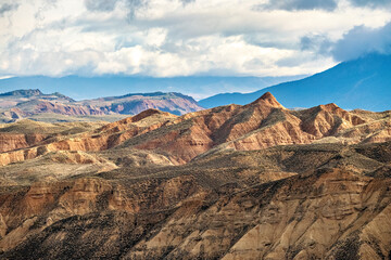 Naklejka premium Sunlit badlands beneath storm clouds in Granada Geopark Spain