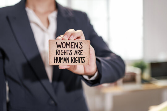 Businesswoman holding a sign that says women's rights are human rights in an office, gender equality, activism and support for social change.