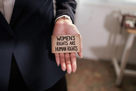 Business person holding a small sign with the message women's rights are human rights, support for equality and women's rights.