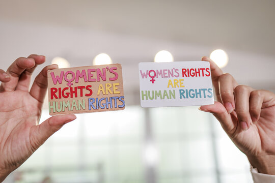 Hands holding small protest signs with the message women&rsquo;s rights are human rights, equality, activism, and social justice