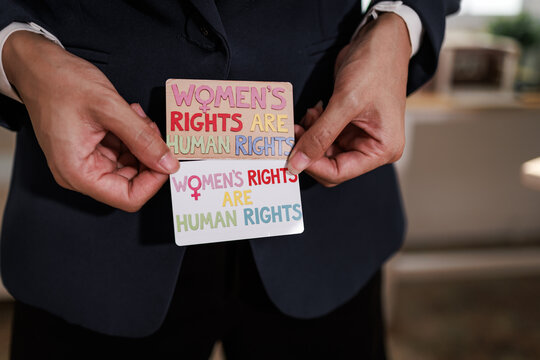 Hands holding cards with women&rsquo;s rights are human rights message, equality and social justice