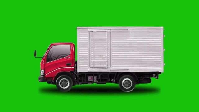  Side view of a red and white delivery cargo truck driving against a green screen background in slow motion
