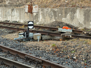 A railroad switch signal stands near metal train tracks with industrial gravel bedding, depicting classic railway infrastructure for transport logistics and transit route safety © Alina
