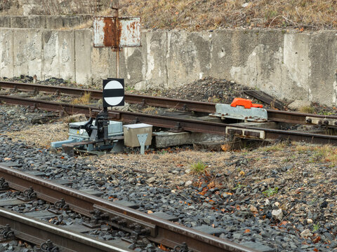 A railroad switch signal stands near metal train tracks with industrial gravel bedding, depicting classic railway infrastructure for transport logistics and transit route safety