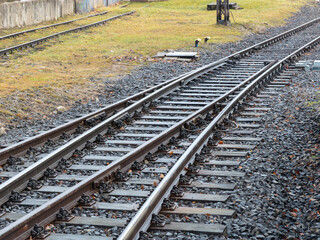 Obraz premium A pair of parallel metal railway tracks curves across a gravel bed, illustrating infrastructure and connectivity in a rural setting where steel rails guide public transportation travel