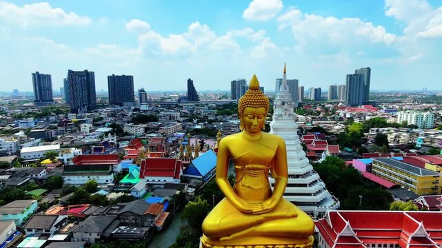 Aerial drone shot flying forward and approaching Giant Golden Buddha at Wat Paknam Phasi Charoen, Bangkok, Thailand