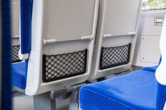 Empty blue and white seats inside a modern train carriage, depicting comfortable public transportation for daily city commuting and regional travel experiences in a clean environment