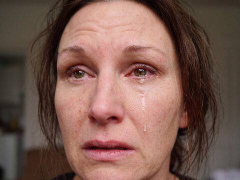 Portrait einer weinenden dunkelhaarigen Frau, die Augen geschwollen und ger&ouml;tet. Tr&auml;nen laufen &uuml;ber ihr Gesicht. 