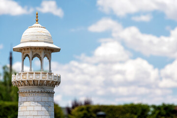 White marble minaret with ornate dome against blue sky and clouds. Features copy space for travel, culture, and historical themes © serebryannikov