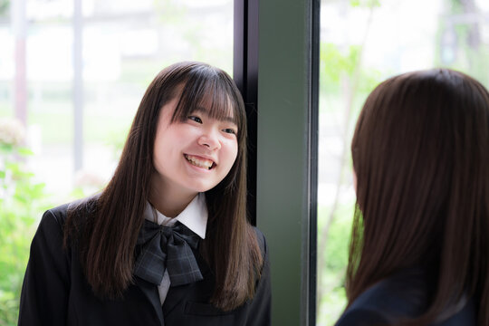 笑顔で会話を楽しむ女子高校生2人　休み時間や放課後の学校生活・友人とのコミュニケーション、青春のイメージ