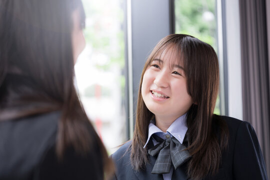 笑顔で会話を楽しむ女子高校生2人　休み時間や放課後の学校生活・友人とのコミュニケーション、青春のイメージ