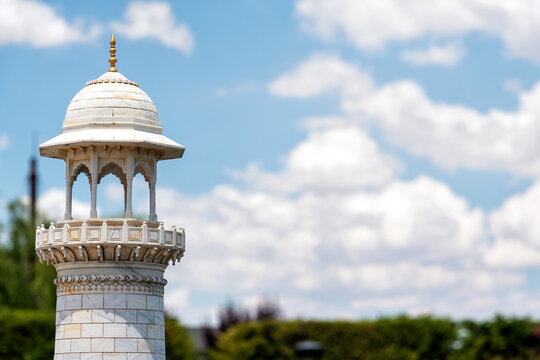 White marble minaret with ornate dome against blue sky and clouds. Features copy space for travel, culture, and historical themes
