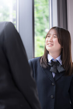 笑顔で会話を楽しむ女子高校生2人　休み時間や放課後の学校生活・友人とのコミュニケーション、青春のイメージ