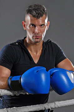 Kick boxing fighter portrait wearing blue boxing gloves on the ring.