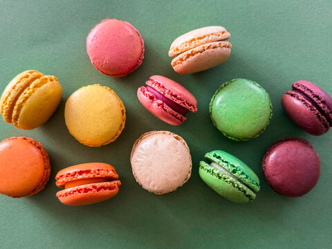 Draufsicht auf bunte Macarons auf einem gr&uuml;nen Hintergrund. Dessert, Frankreich.