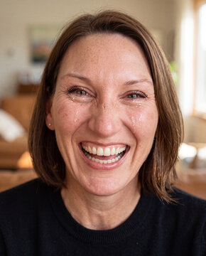 Portrait einer lachenden dunkelhaarigen Frau. Tr&auml;nen laufen &uuml;ber ihr Gesicht, weil sie nicht aufh&ouml;ren kann, zu lachen. 
