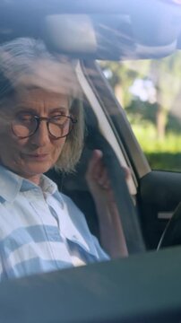 Serious confident Caucasian retired old woman sitting inside own renting car fastening seat belt senior mature female driver client automobile buying test drive in city ready to driving granny in auto