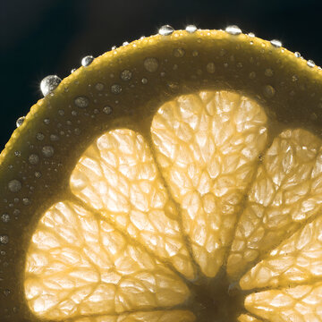 Citrus fruit slice with water droplets backlit, close-up macro of juicy texture
