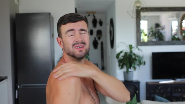 Man applying heating patch to relieve severe shoulder blade and back pain