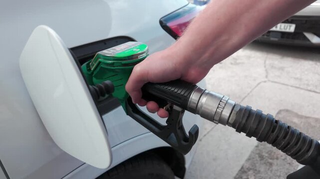Cutaway shot. CU of hand filling car at petrol station. 