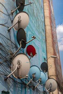 Cluster of satellite dishes mounted on a residential building, illustrating urban communication infrastructure and telecommunications technology