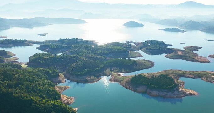 Spectacular sunrise over Ham Thuan Lake, a large hydroelectric reservoir in Lam Dong, Vietnam. Golden morning sunlight reflects on the calm water surface