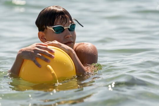 Teenage swimmer resting with a swim buoy during an open water session. Healthy summer outdoor activity promoting water safety, confidence and an active lifestyle.