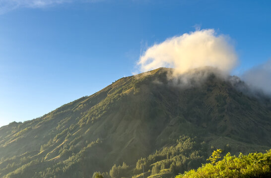 Cloud drifting over the summit of Mount Batur volcano under a clear blue sky at sunrise, Kintamani, Bangli, Bali, Indonesia.