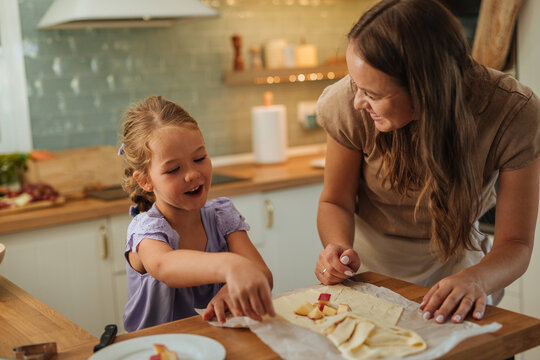 Mother and daughter baking fruit pastry in kitchen