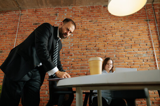 Boss looking over employee shoulder creating workplace tension