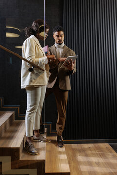 Business colleagues collaborating on tablet near office staircase