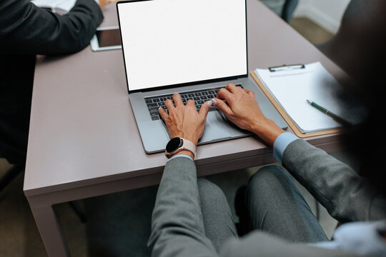 Business professional typing on laptop during meeting at desk