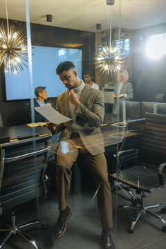 Young businessman analyzing document in modern office meeting