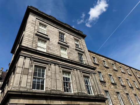 Historic stone building facade in Dublin, Ireland with classical windows and cornice under blue sky