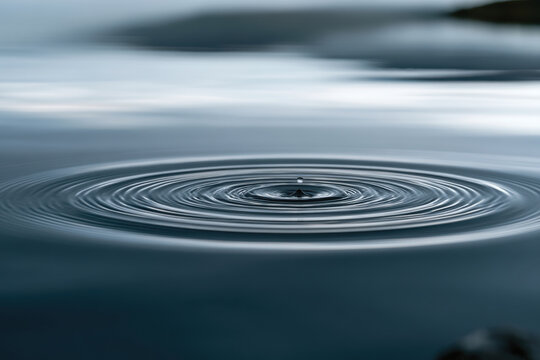 A serene image depicting a close-up view of calm water with perfectly circular ripples, highlighting the tranquility and beauty found in natural water bodies.