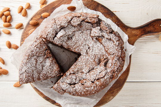 classic Italian Torta Caprese is a rich chocolate and almond flour cake closeup on the wooden board on the table. Horizontal top view from above